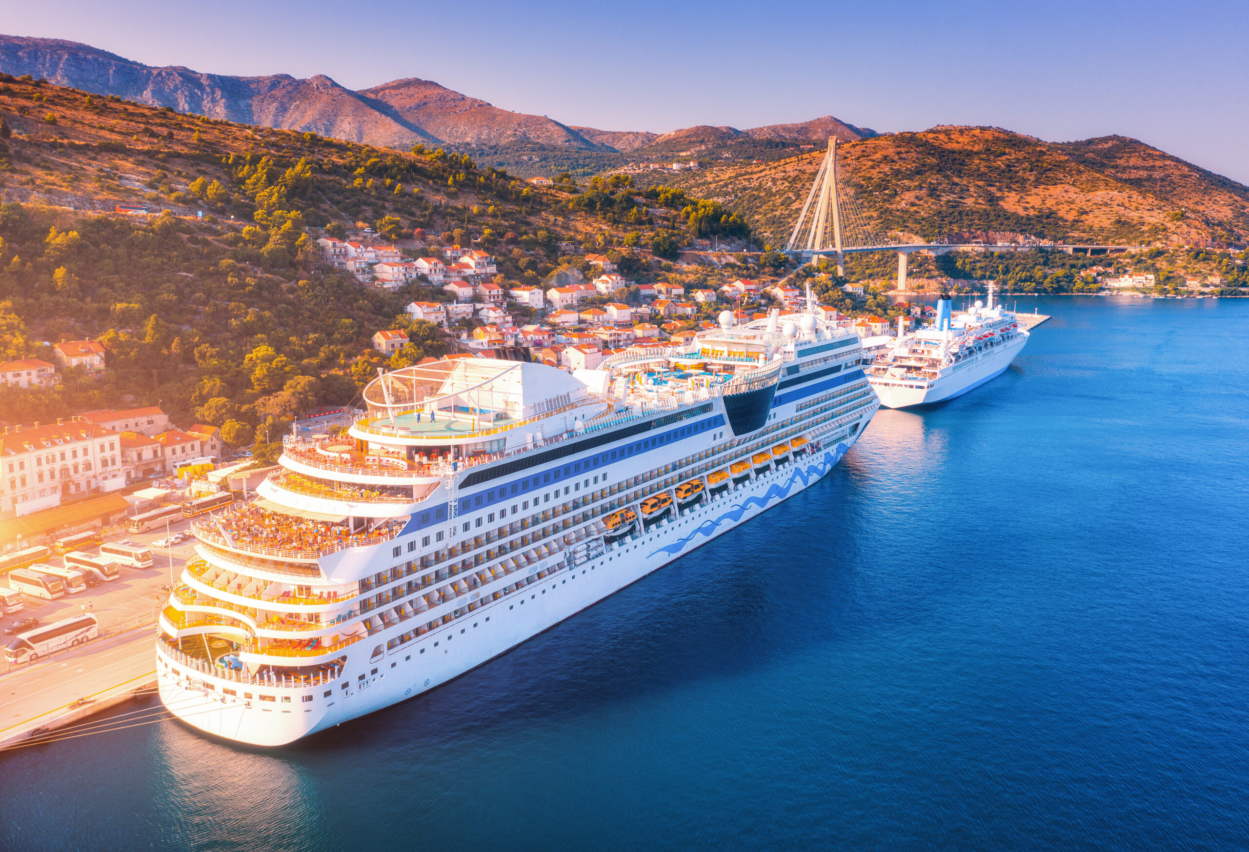 Aerial view of cruise ship at harbor at sunset. beautiful large ships and boats. Landscape with boats in harbour, city, mountains, blue sea. Top view of yacht. Luxury cruise. Floating liner in port