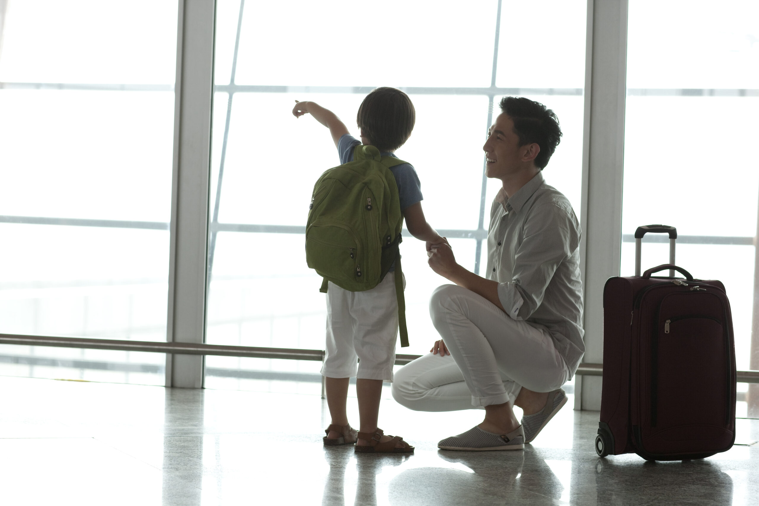 Chinese father and son looking at view at the airport