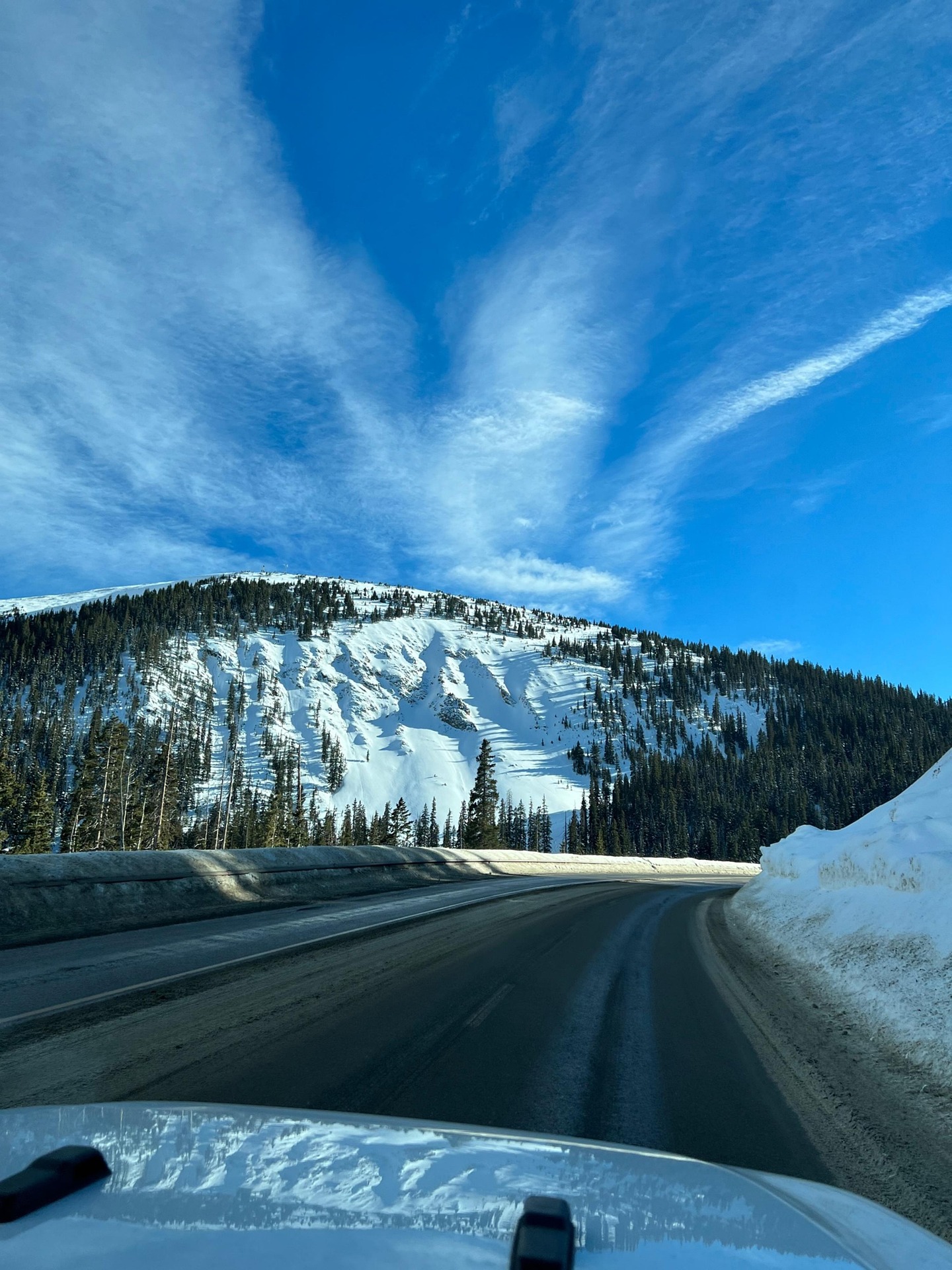 car driving on a road in denver, co. snowy mountains in the background